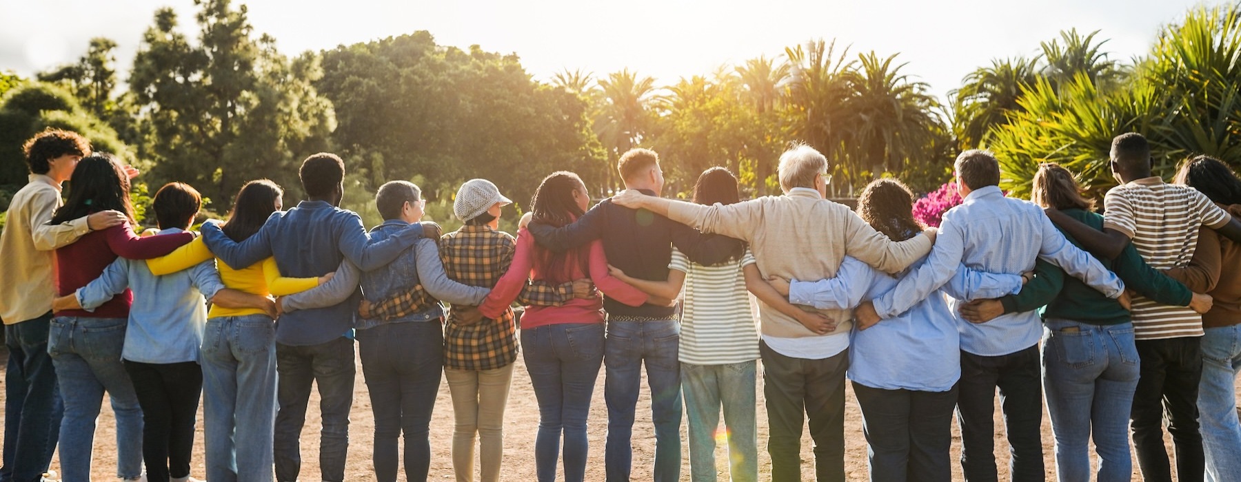 a group of people facing a landscape with the sun setting