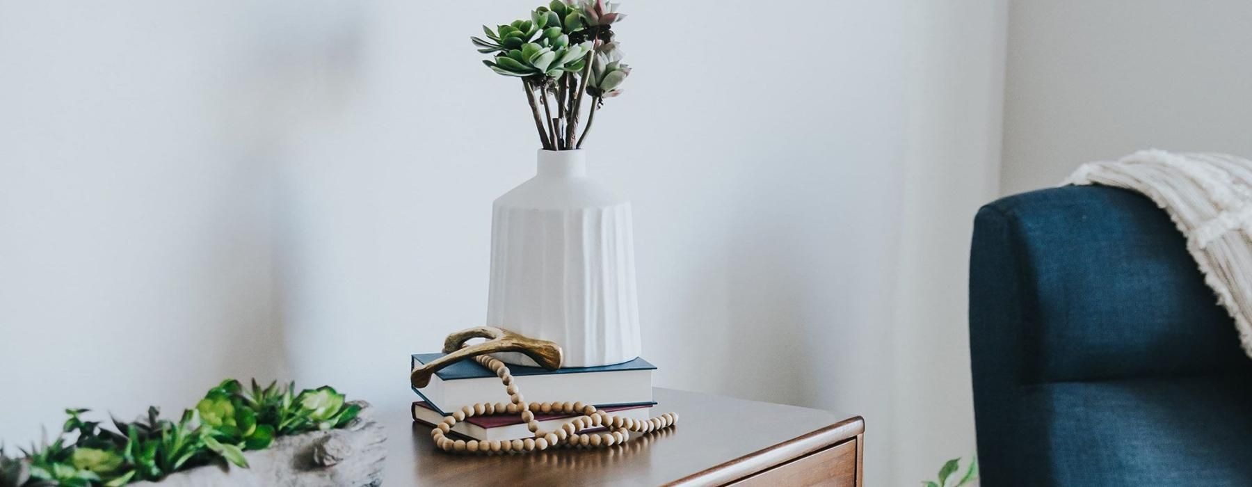 a dresser with a vase of plants on top